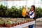 Young pretty Asian woman working in greenhouse watering the plants