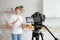 A young pretty blogger girl is recording a video tutorial on cooking salads in a home kitchen.