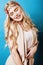 Young pretty blond girl with curly blond hair and little lowers happy smiling on blue sky background