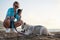 Young pretty blond woman, taking picture on her phone of her small husky puppy. Owner and the light grey dog, playing on the sandy