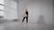 Young pretty blonde woman is rehearsing her dance performance in white dancing hall, jumping and rotating