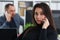 Young pretty brunette woman in office work with her boss hold smartphone in hands
