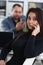 Young pretty brunette woman in office work with her boss hold smartphone in hands