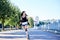 Young pretty brunette woman, riding roller blades in city park in the morning. Fit sporty girl, wearing black top and white shorts