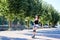 Young pretty brunette woman, riding roller blades in city park in the morning. Fit sporty girl, wearing black top and white shorts