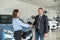 young pretty client shaking hands with man sales dealer in modern car showroom