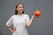 Young pretty European woman wearing white t-shirt, prepares for special holiday, holding ripe orange pumpkin