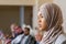 Young pretty female speaker in hijab talking to audience at conference
