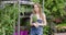 Young pretty gardener woman posing at stand with potted flowers