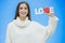 Young pretty girl dressed in white clothes. During this time it stands on a blue background. Holds a word of love in