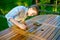 Young pretty girl holding a brush applying varnish paint on a wooden garden table