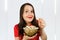 Young pretty girl with opened mouth and wide eyes holds glass bowl with popcorn