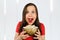 Young pretty girl with opened mouth and wide eyes holds glass bowl with popcorn