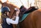 Young pretty girl preparing horse for riding