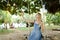 Young pretty girl riding swing and making selfie by smartphone, sand and trees in background.