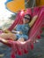 Young pretty happy Asian Chinese woman lying lazy on beach hammock sun bed relaxed and cheerful in Summer holiday trip enjoying va