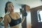 Young pretty and happy Asian Chinese woman working hard at hotel gym or fitness center lifting dumbbell doing body building