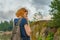 Young pretty lady with backpack walking outdoors in summer evening. Tourist on the beautiful landscape background.