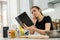 Young pretty lady reading notebook with recipe taste cake of flour, oil and other ingredient