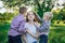 Young pretty mother with two sons sit in the park. Children kiss and hug mom