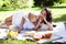 Young pretty pregnant brunette woman having fun with her daughter on picnic on green grass in park, lifestyle people