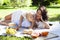 Young pretty pregnant brunette woman having fun with her daughter on picnic on green grass in park, lifestyle people