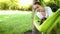 Young pretty smiling woman with cute Welsh Corgi dog lying in bright green hammock in park