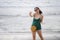 Young pretty and sweet Chinese Asian woman on the beach taking selfie picture portrait with mobile phone camera enjoying holiday h