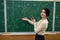 young pretty teacher learn lesson on chemistry and standing near blackboard with chemical formula