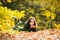 Young pretty teenage girl at autumn park. Portrait of young girl relax outdoor. Leaves falling.