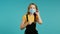 Young pretty teenager girl puts on face medical mask during coronavirus pandemic. Portrait on blue background