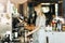 A young pretty thin blonde with long hair,dressed in casual outfit,is cooking coffee in a modern coffee shop. Process of