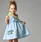 Young pretty toddler girl kid with big sweet lollypop candy in blue dress on grey