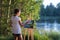 Young pretty woman artist draws paints a picture of lake on open plain air outdoors