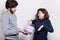 Young pretty woman being surprised to receive present from her boyfriend. Young beautiful couple standing near white wall. Bearded