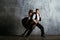 Young pretty woman in black dress and man dance tango