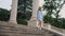 Young pretty woman in blue dress is walking down large beautiful city staircase