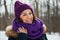 Young pretty woman with happy smile in purple snood and hand-knitted hat.