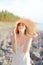 Young pretty woman in hat standing on shingle beach.