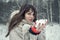 Young pretty woman having fun in the winter forest with snow in hands