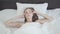 Young pretty woman lying in bed in the morning. The girl just woke up and stretching lying under the blanket. Leisure at