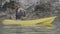 Young pretty woman paddling a yellow sea kayak in a tropical resort..