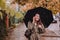 young pretty woman portrait listening music with headset while walking by street with umbrella under rain