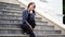 Young pretty woman poses on stairs of manor. Adult smiley female sitting on steps of Palace.