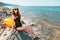 Young pretty woman posing sitting on the rocky beach next to the swimming circle. The concept of holiday resort and travel