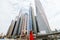 Young pretty woman in red dress and straw hat pointed with hands on downtown skycrapers in modern city. Low angle view