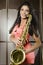 Young pretty woman with saxophone playing on party