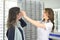 Young pretty woman is trying eye glasses on at an eyewear shop with help of a shop assistant