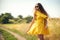 young pretty woman walks on field in summer while wearing a sunglasses and yellow dress. Lifestyle