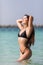 Young pretty womanin black bikini in water playfull on the beach